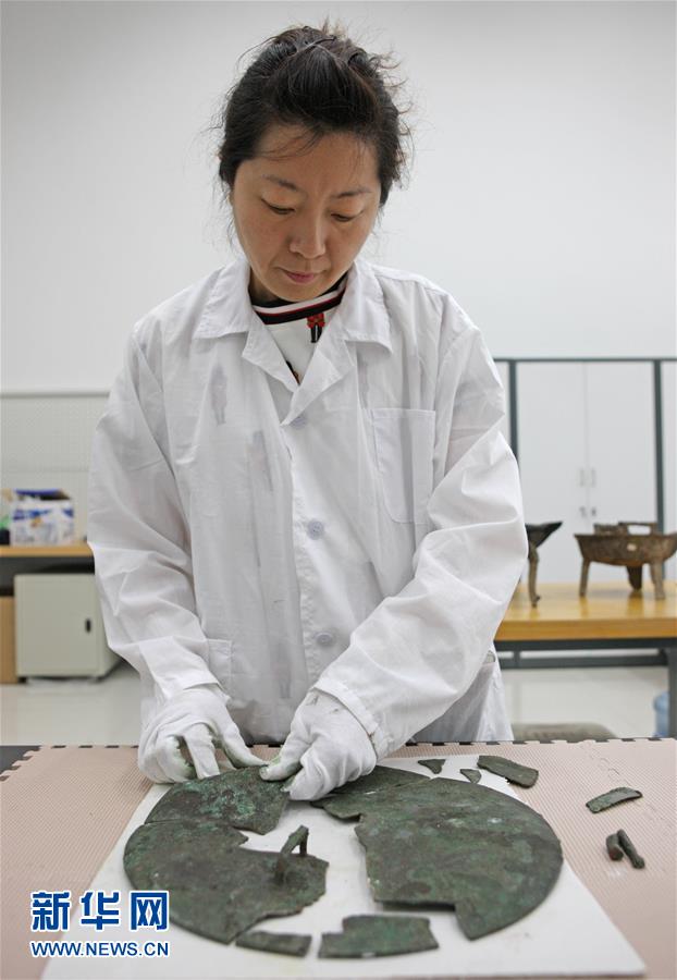 5月17日，文物修复技师张芯语在去除画卷上的附着物。