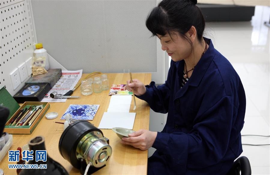 5月17日，文物修复技师张芯语在去除画卷上的附着物。