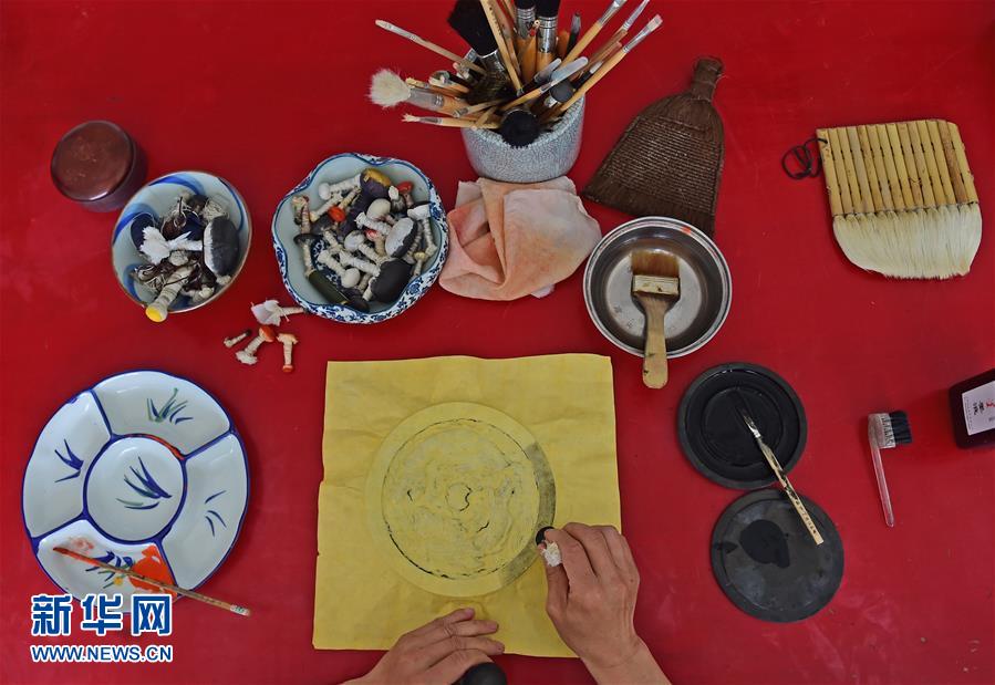 5月17日，文物修复技师张芯语在去除画卷上的附着物。