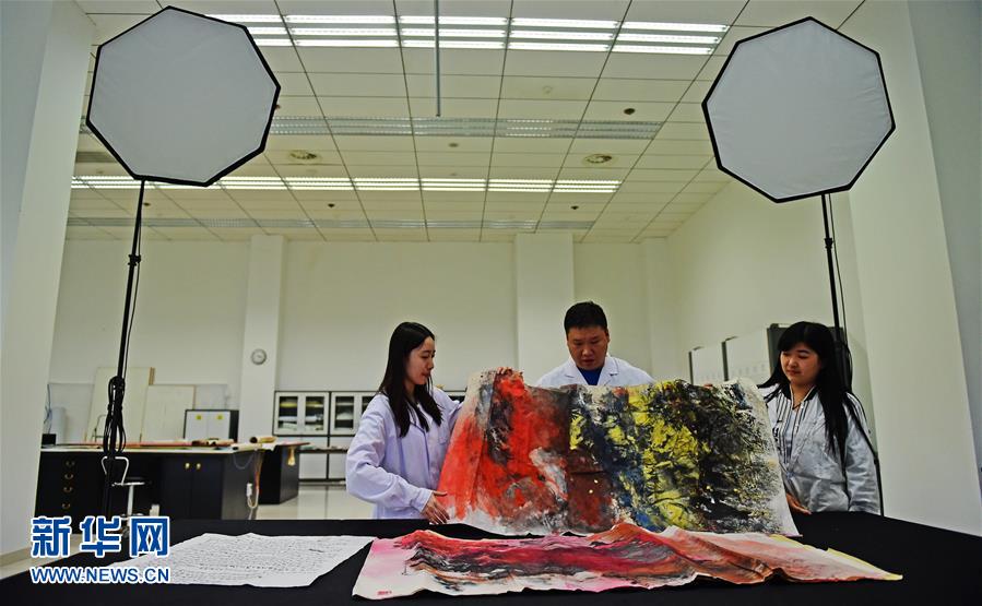 5月17日，文物修复技师张芯语在去除画卷上的附着物。