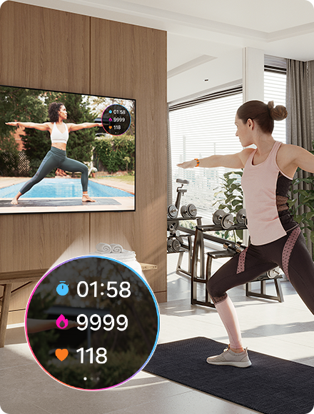 Woman does yoga while watching a trainer on TV. TV also shows exercise stats 01:58, 9999, 118 from connected Galaxy Watch.